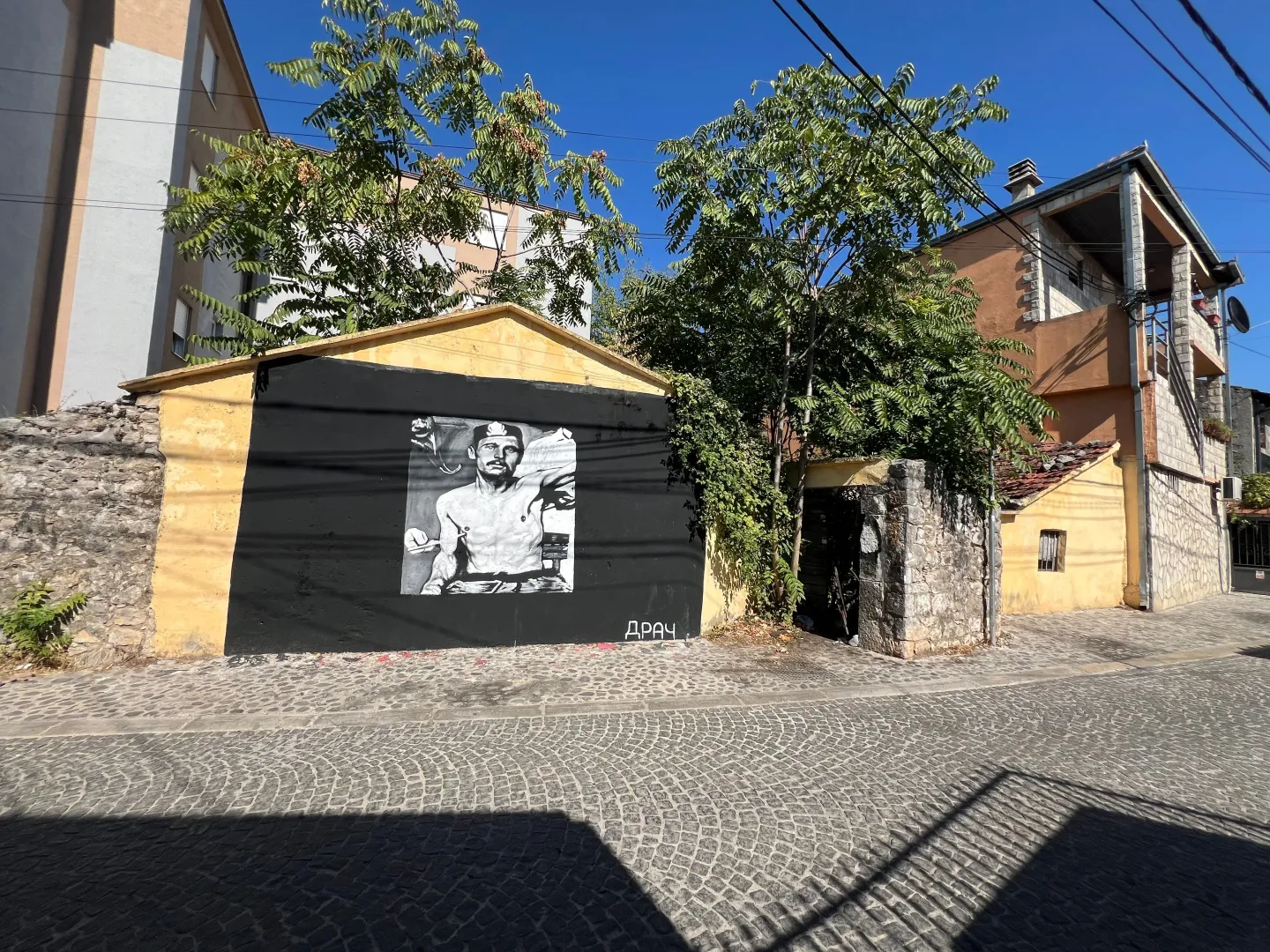 Eksterijer kuće sa muralom i popločanim dvorištem.