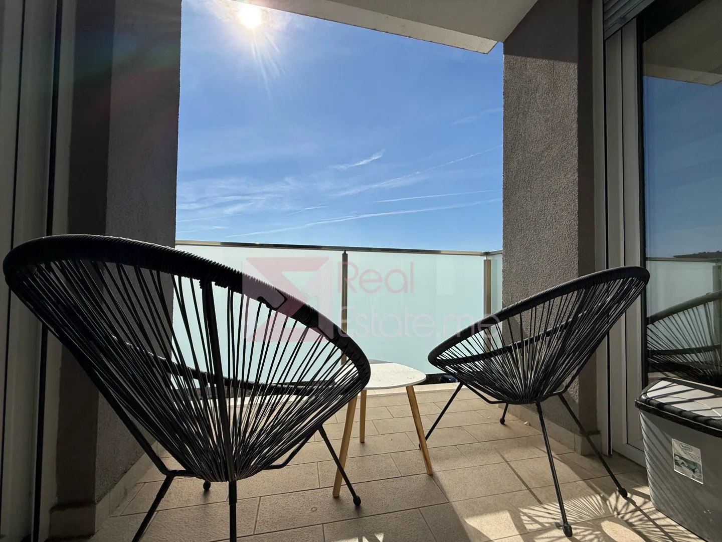 Furnished terrace with two black chairs and a view of the sky.