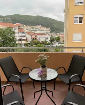 Furnished balcony with a table, chairs, and a view of the city and hills. - image 2