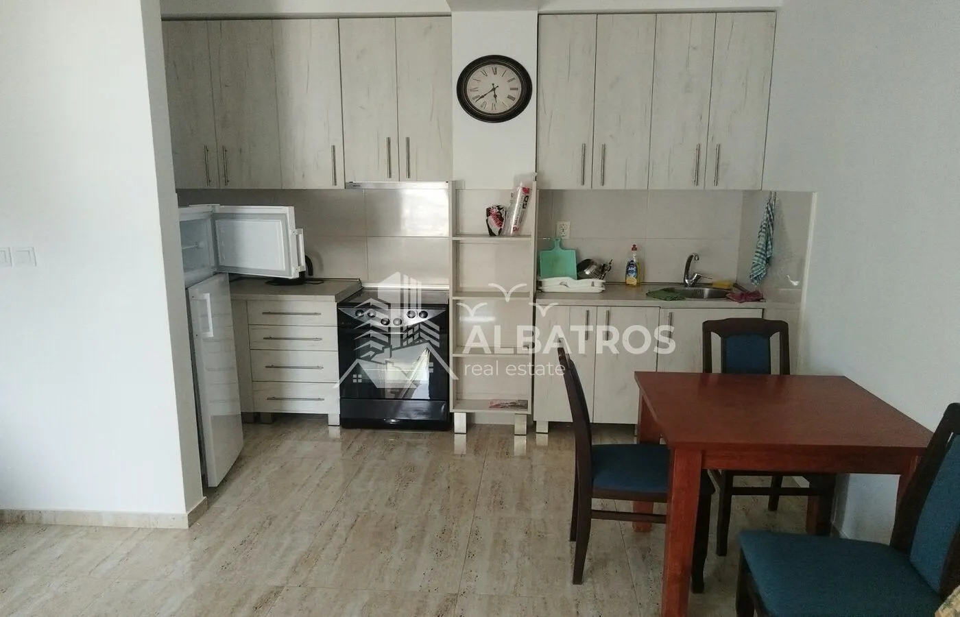 Small kitchen with light-coloured cabinets and a dining table.