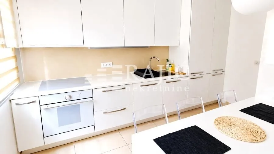 Modern kitchen with white cabinetry and a dining table.