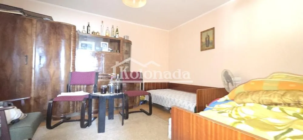 Nameštena spavaća soba sa krevetom, ormarom i stolom sa stolicama.