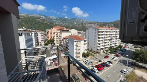 Pogled sa balkona na okolne zgrade i planine u pozadini. - image 11