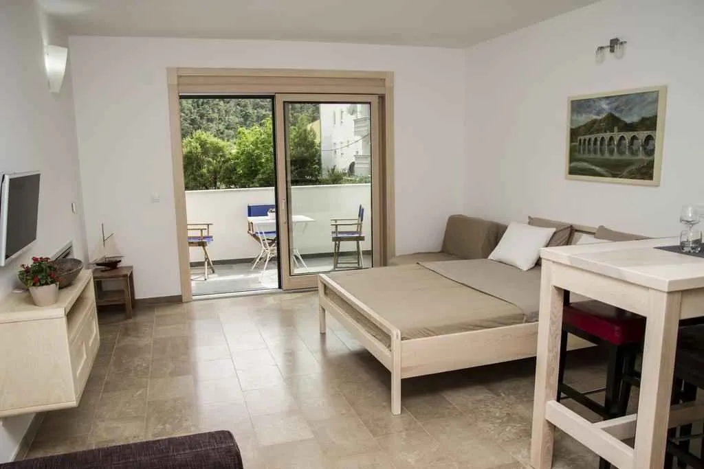 Svijetao studio apartman sa krevetom i izlazom na balkon.