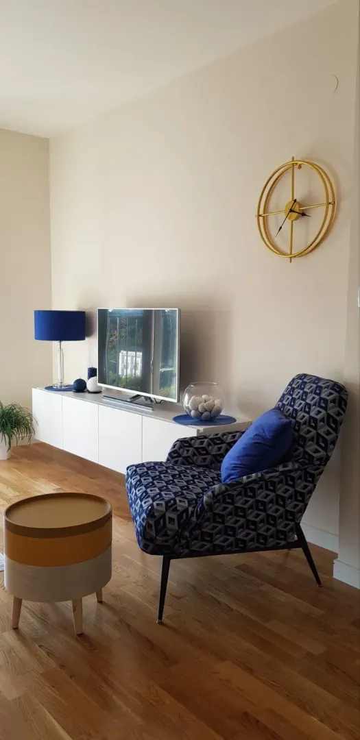 Living room with an armchair, TV unit, and decorative items.