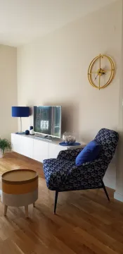 Living room with an armchair, TV unit, and decorative items. - image 3