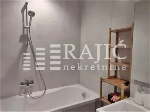 Smaller bathroom with a bathtub, shower mixer, and wooden shelf. - image 10