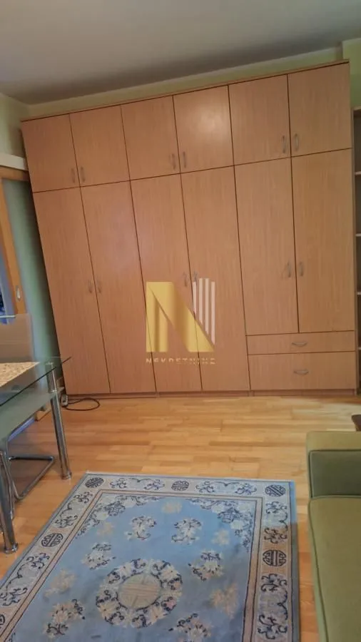 Dnevna soba sa velikim drvenim ormarom i parketom.
