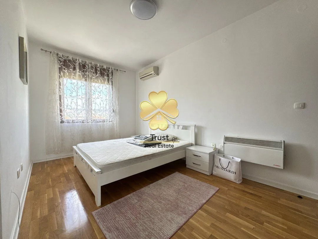 Bright bedroom with a double bed, laminate flooring, and a window.