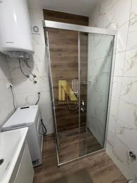 Bathroom with a shower cabin, water heater, and washing machine. - image 9