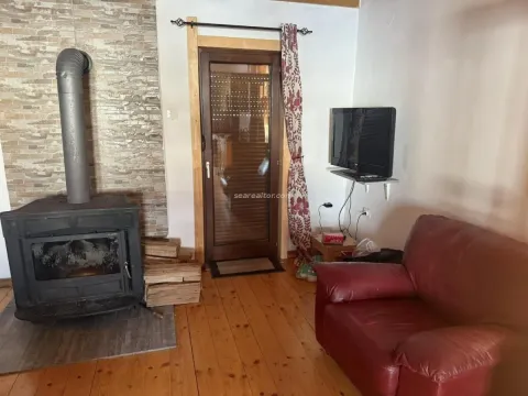 Living room with a wood-burning stove and wooden flooring. - image 10