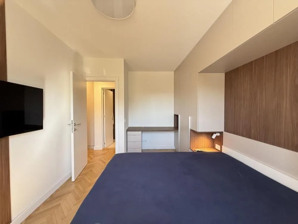 Furnished bedroom with a double bed, built-in wardrobes, and a desk.