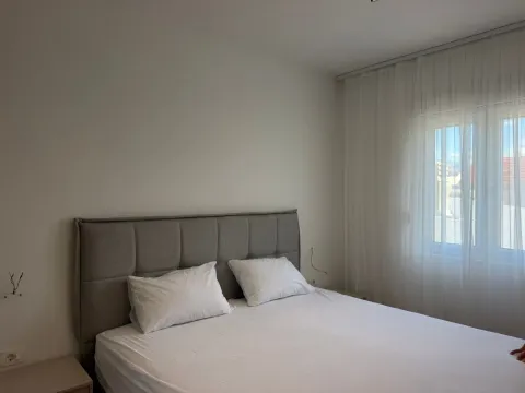 Bright bedroom with a double bed and a window covered by a white curtain. - image 8