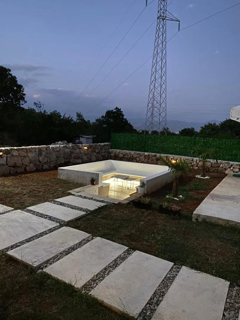 Landscaped yard with modern sunken seating and walkway at dusk.