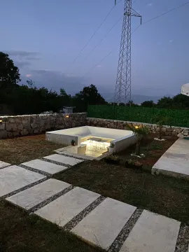 Landscaped yard with modern sunken seating and walkway at dusk. - image 6