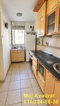 Manja kuhinja sa drvenim elementima i belim frižiderom. - image 4