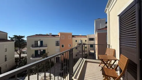 Manji namješteni balkon sa drvenim stolom i stolicama i pogledom na naselje. - image 6