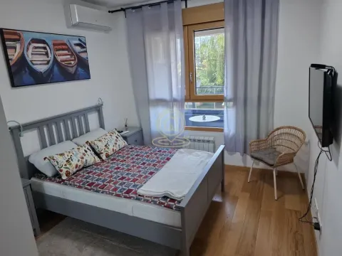 Nameštena spavaća soba sa bračnim krevetom, TV-om i prozorom sa zavesama. - image 6