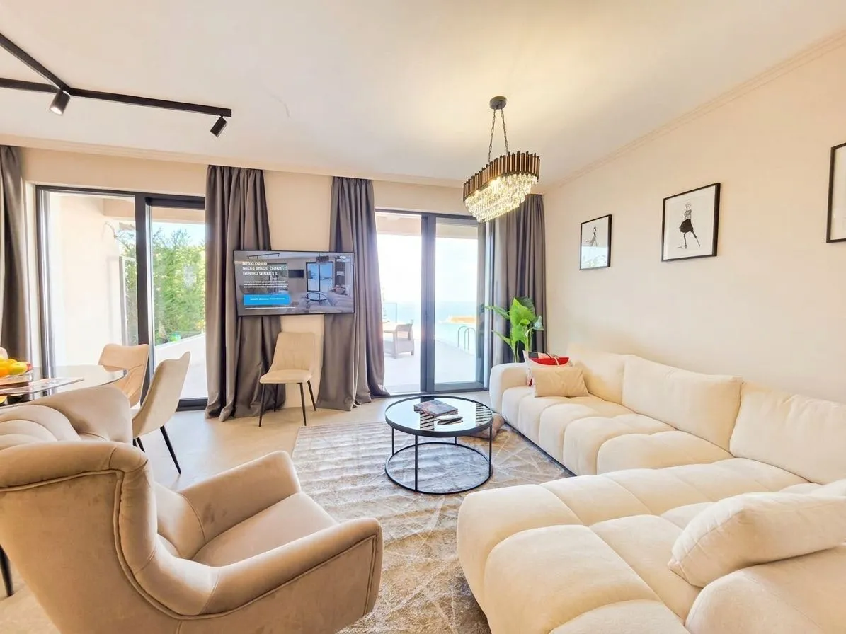 Spacious living room with a sofa, armchair, dining table, and access to the terrace.