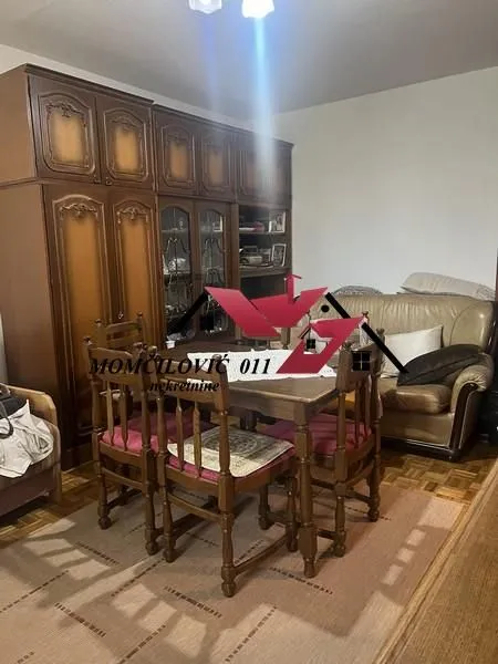 Dnevna soba sa trpezarijskim stolom, garniturom i masivnim drvenim ormanom.
