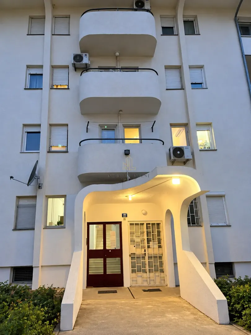 Main entrance of an apartment building with balconies on the upper floors.