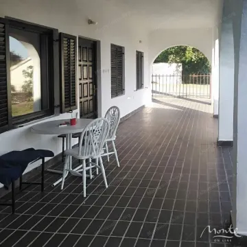 Covered terrace with a table and chairs in front of the house entrance. - image 7