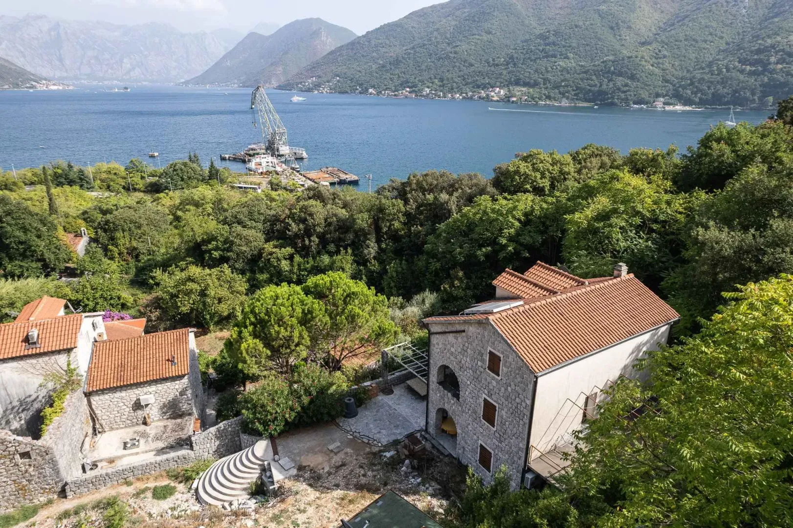 Pogled iz vazduha na kamenu kuću sa dvorištem i pogledom na zaliv.