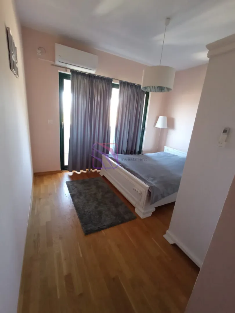 Spavaća soba sa bračnim krevetom, drvenim podom i izlazom na terasu.
