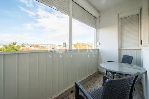 Enclosed balcony with seating furniture and a city view. - image 8