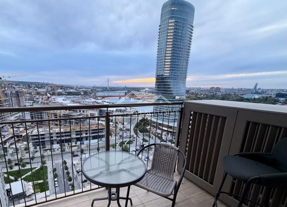 Namešten balkon sa stolom, stolicama i pogledom na grad.