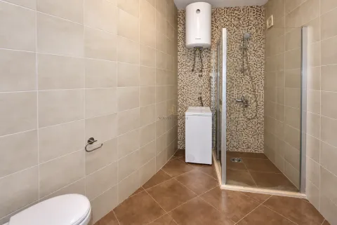 Bathroom with a shower cabin, water heater, and washing machine. - image 12