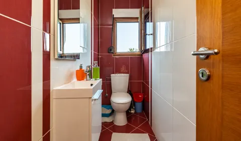 Manje kupatilo sa umivaonikom, toaletom i crveno-bijelim pločicama. - image 14
