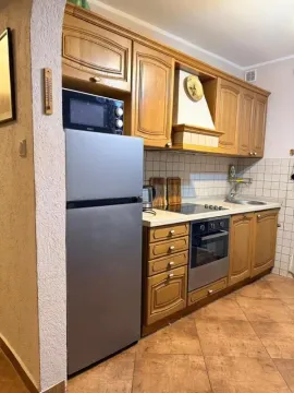 Kitchen with wooden cabinetry, refrigerator, and built-in appliances. - image 5