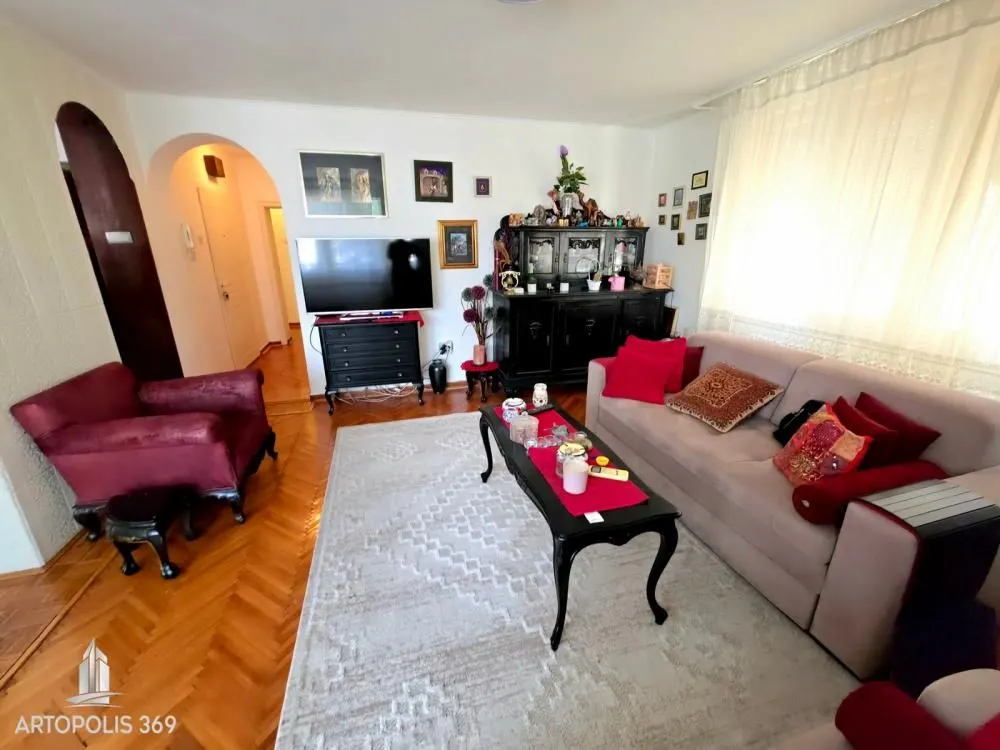 Dnevna soba sa garniturom, foteljom i televizorom.