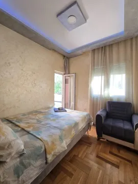 Namještena spavaća soba sa krevetom, foteljom i izlazom na terasu. - image 5
