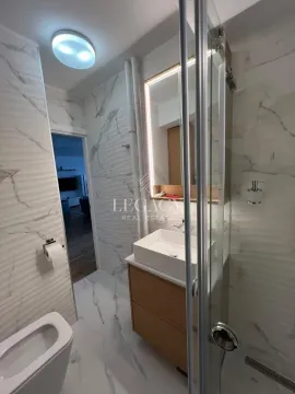 Modern bathroom equipped with a shower cabin, washbasin, and marble tiles. - image 14