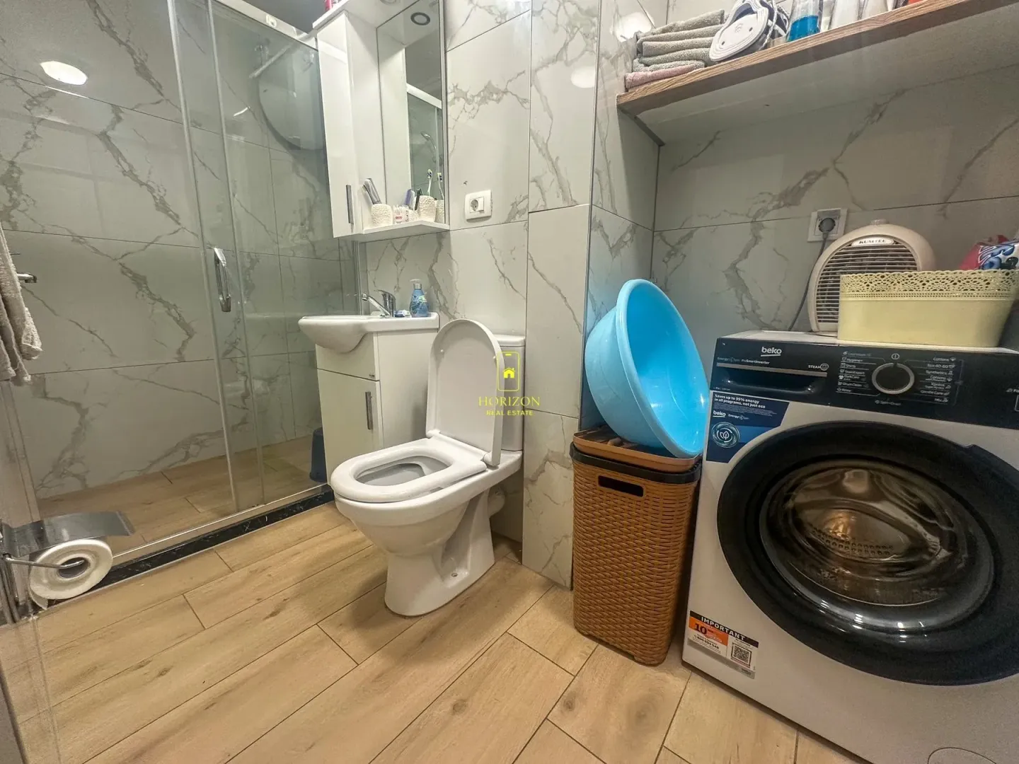 Moderne kupatilo sa tuš kabinom, umivaonikom, toaletom i veš mašinom.