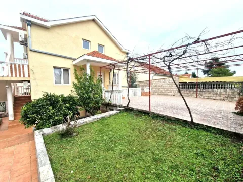 Pogled na dvorište i spoljašnjost kuće sa popločanom terasom i pergolom. - image 3