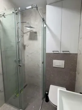 Moderne kupatilo sa tuš kabinom i bijelim visećim ormarićem. - image 3