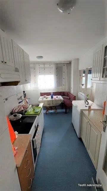 Small kitchen with an adjoining dining area and white kitchen cabinets.
