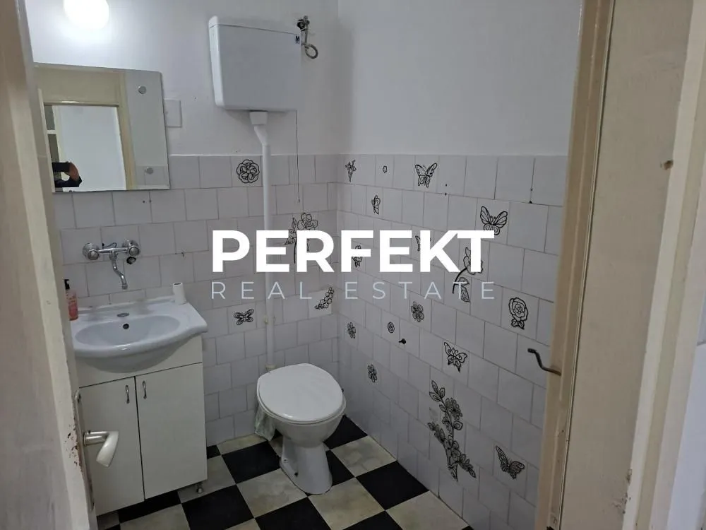 Manje kupatilo sa umivaonikom, toaletom i pločicama sa dezenom leptira.