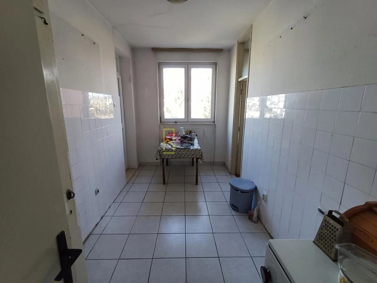 Manja kuhinja sa pločicama na zidovima i trpezarijskim stolom.