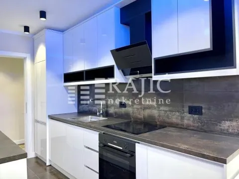 Modern white kitchen with dark countertops and built-in appliances. - image 4