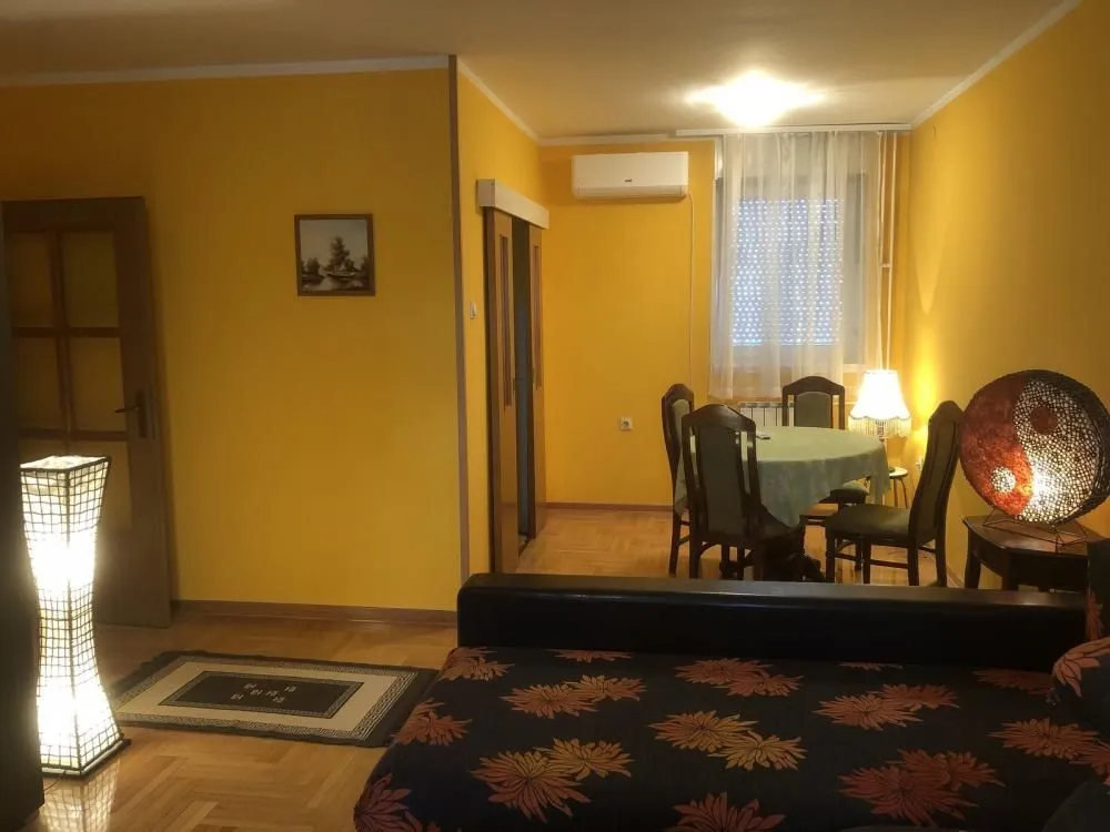 Living room with a sofa set and a dining area in the background.