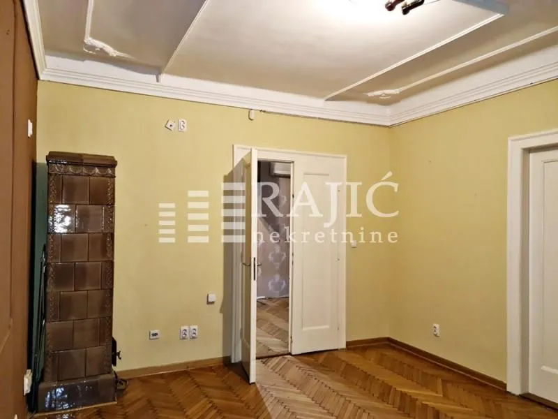 Interior of a room with parquet flooring and a tiled stove.