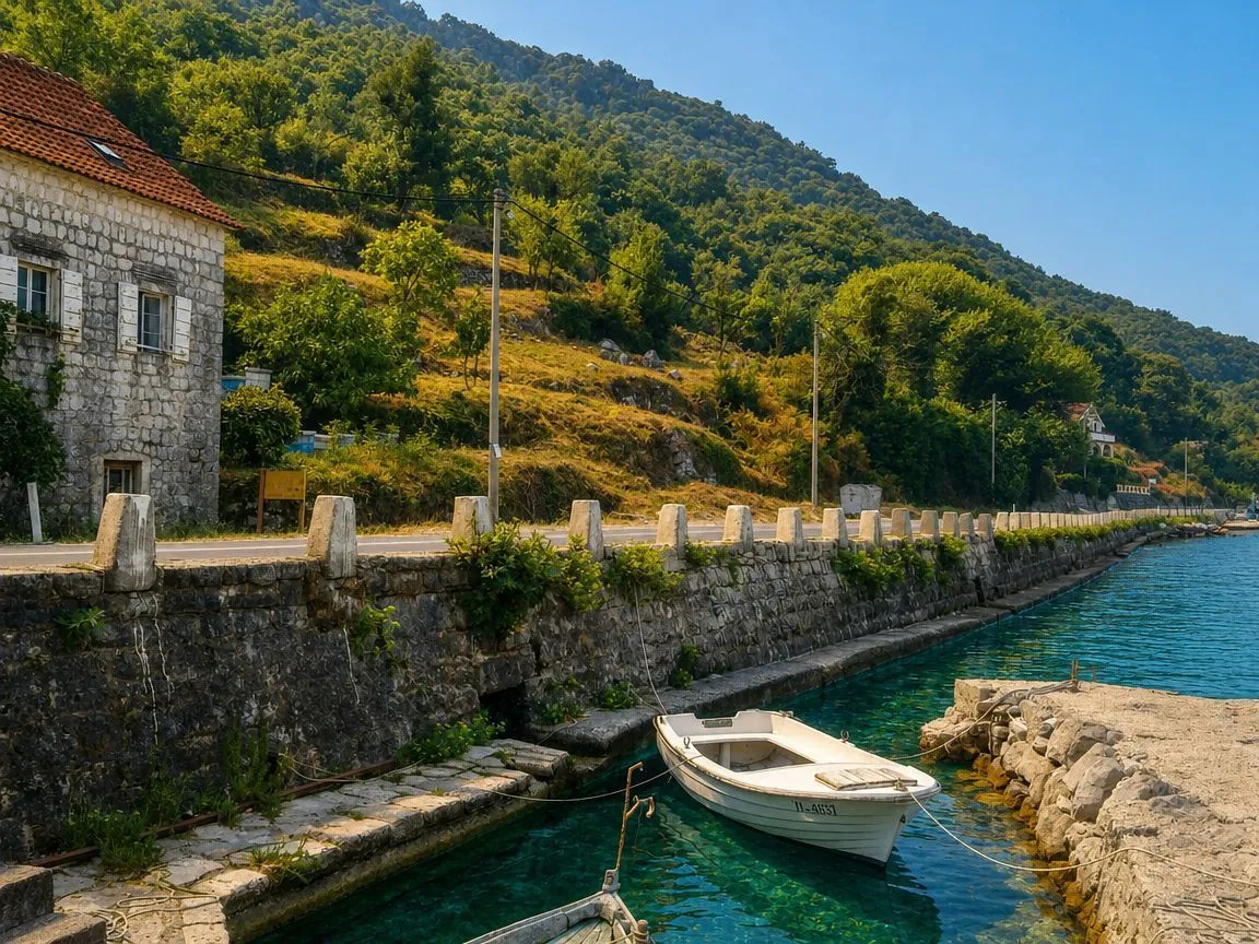 Pogled na kamenu kuću pored obale sa privezanim čamcem.