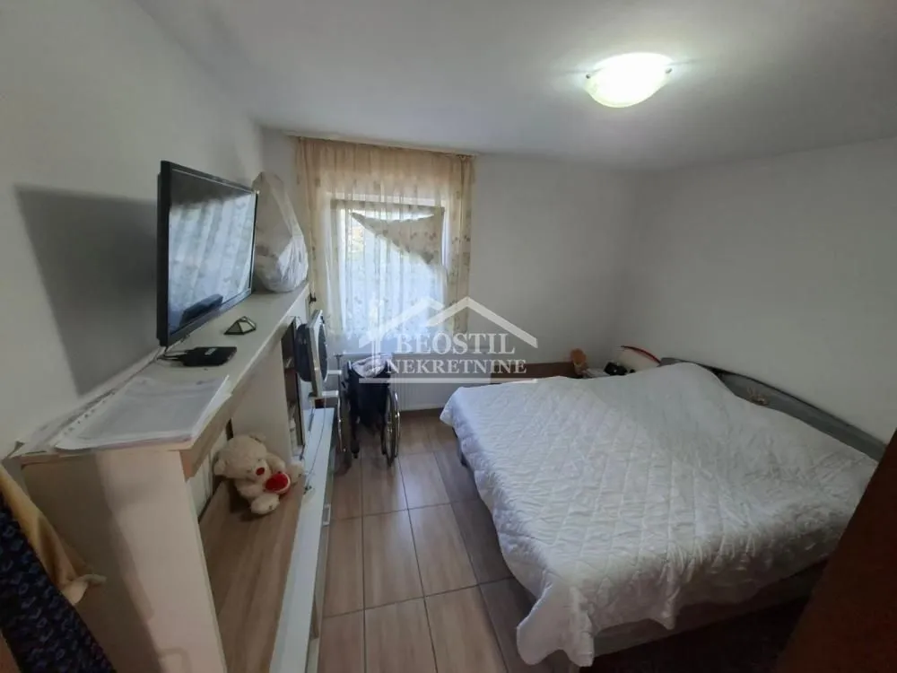 Nameštena spavaća soba sa bračnim krevetom, televizorom i pločicama na podu.