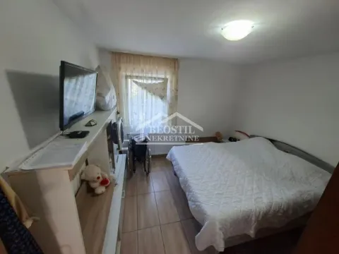 Nameštena spavaća soba sa bračnim krevetom, televizorom i pločicama na podu. - image 5