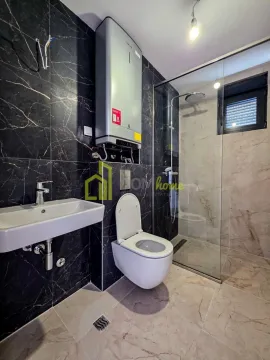 Modernly equipped bathroom with a walk-in shower, washbasin, and toilet. - image 19