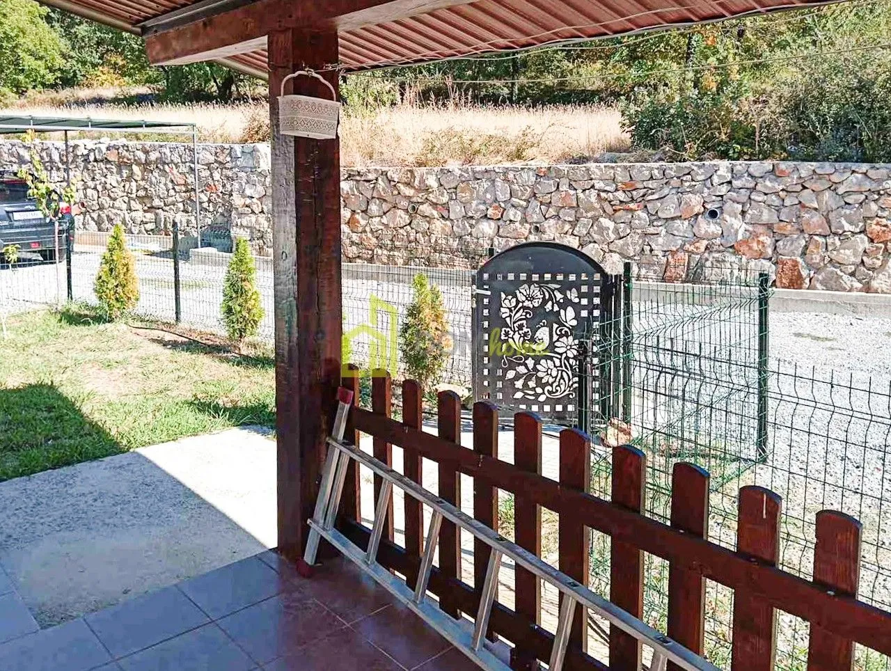 View from the covered terrace towards the yard with a fence and gate.